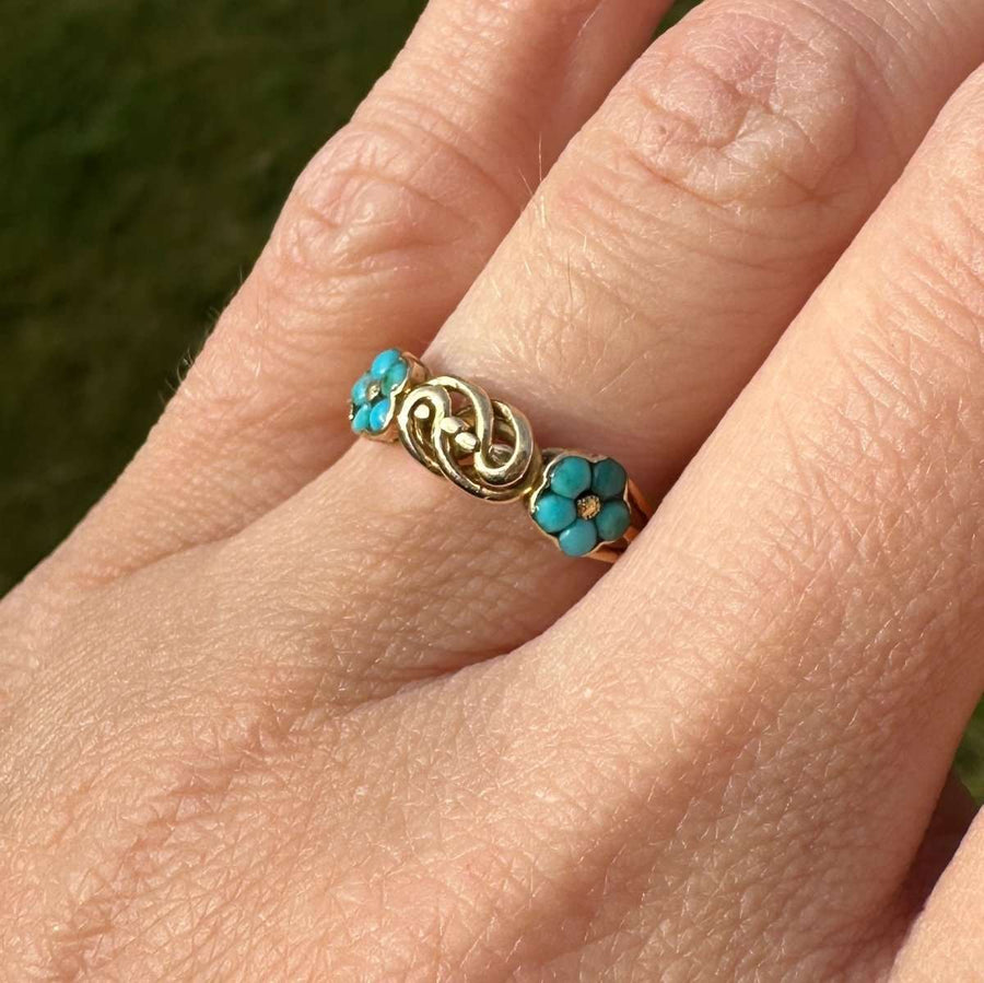 Ring aus 18 Karat Gold mit türkisfarbenen Vergissmeinnicht-Blüten und goldenem Liebesknoten, der Liebe und Erinnerung symbolisiert.