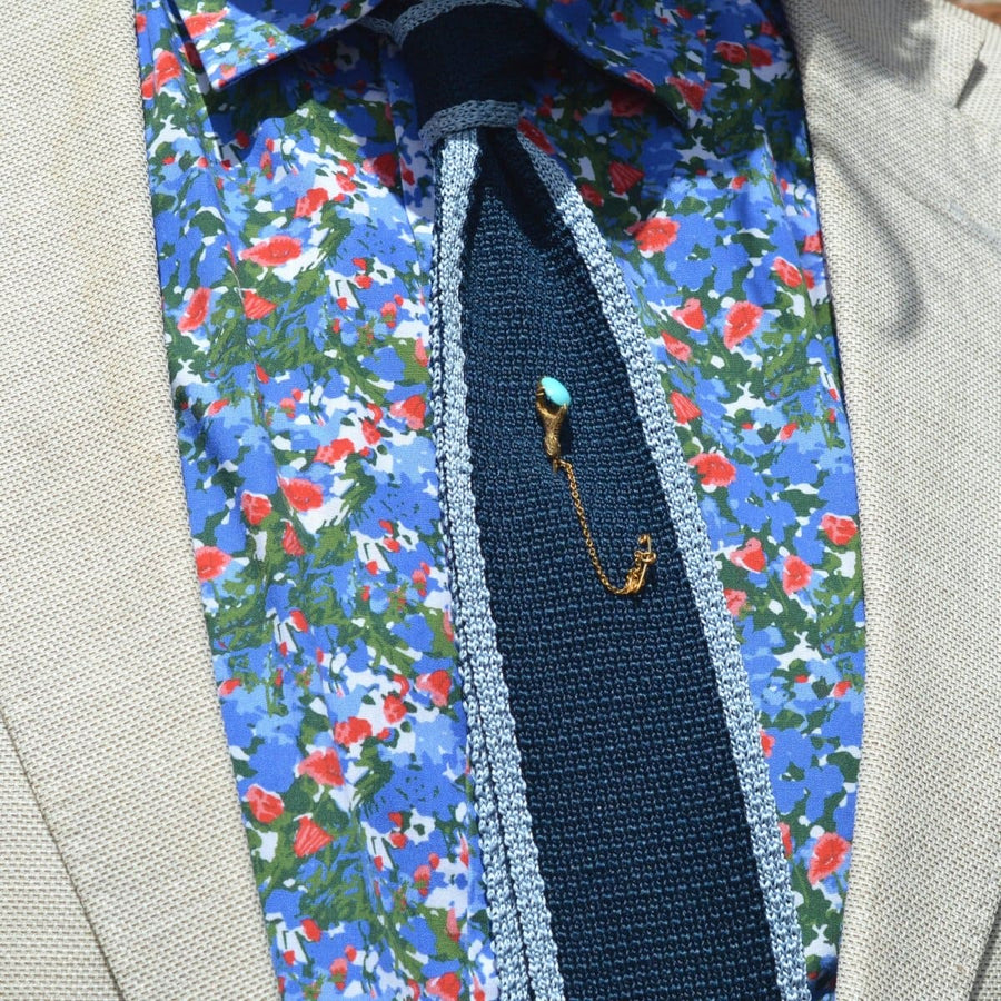 Viktorianische Krawattennadel aus 15-karätigem Gold mit einer Adlerkralle, die einen Türkis hält, getragen auf einem blumengemusterten Hemd.