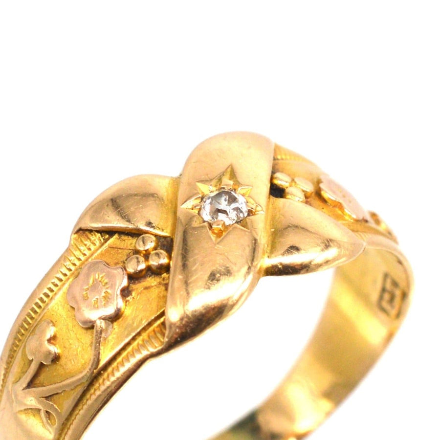 Viktorianischer Kussring aus 18-karätigem Gold mit floralen Motiven und einem zentralen Diamanten, der Liebe und Wachstum symbolisiert.