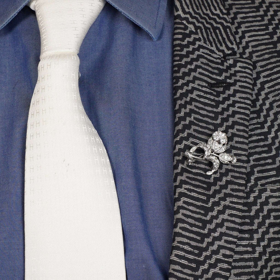 Elegante Blumenbrosche aus Weißgold aus den 1950er Jahren, getragen an einer Anzugsjacke mit weißer Krawatte.