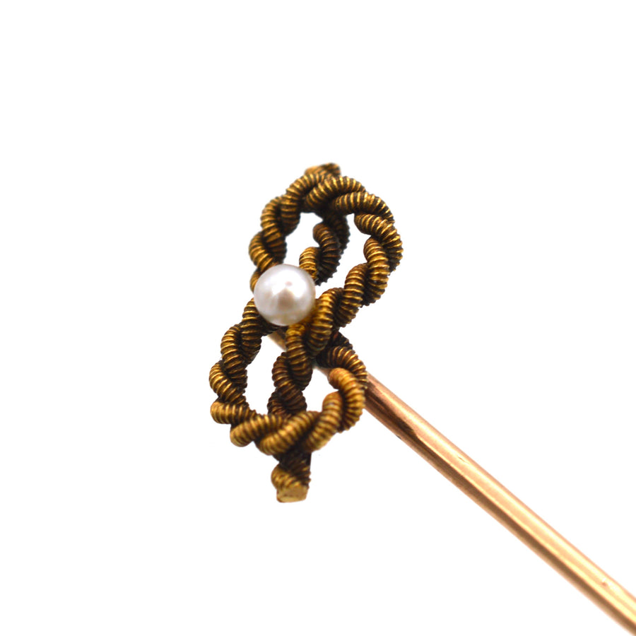 Edwardian 15ct gold lovers knot tie pin featuring a natural pearl, symbolizing infinite love, circa 1900.