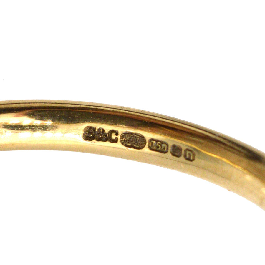 Nahaufnahme eines modernen Eherings aus 18 Karat Gold mit Reinheitszeichen und glattem Design zum Stapeln oder als Ehering.