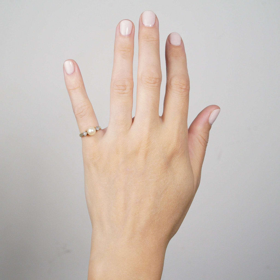 Art-Deco-Ring aus 14-karätigem Gold mit Zuchtperlen und Diamanten, der an einer Hand mit neutralem Nagellack präsentiert wird.
