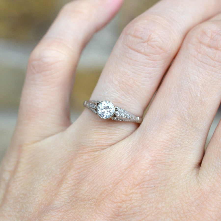 Solitärring aus 18-karätigem Gold und Diamanten im Art-Déco-Stil, der an einer Hand getragen wird, mit einem zentralen Diamanten und verzierten Schultern.