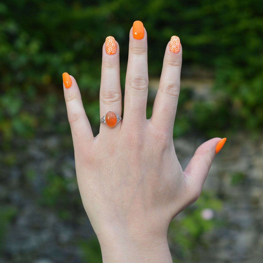 Handgetragener Art-Deco-Ring aus 18-karätigem Weißgold und Platin mit natürlichem mexikanischem Feueropal, der mit leuchtend orangefarbenem Nagellack versehen ist.