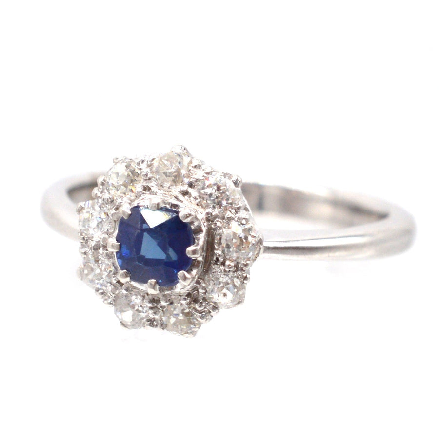 Art-Deco-Ring aus 18 Karat Weißgold mit einem blauen Saphir und Diamanten in der Mitte, umgeben von funkelnden Diamanten.