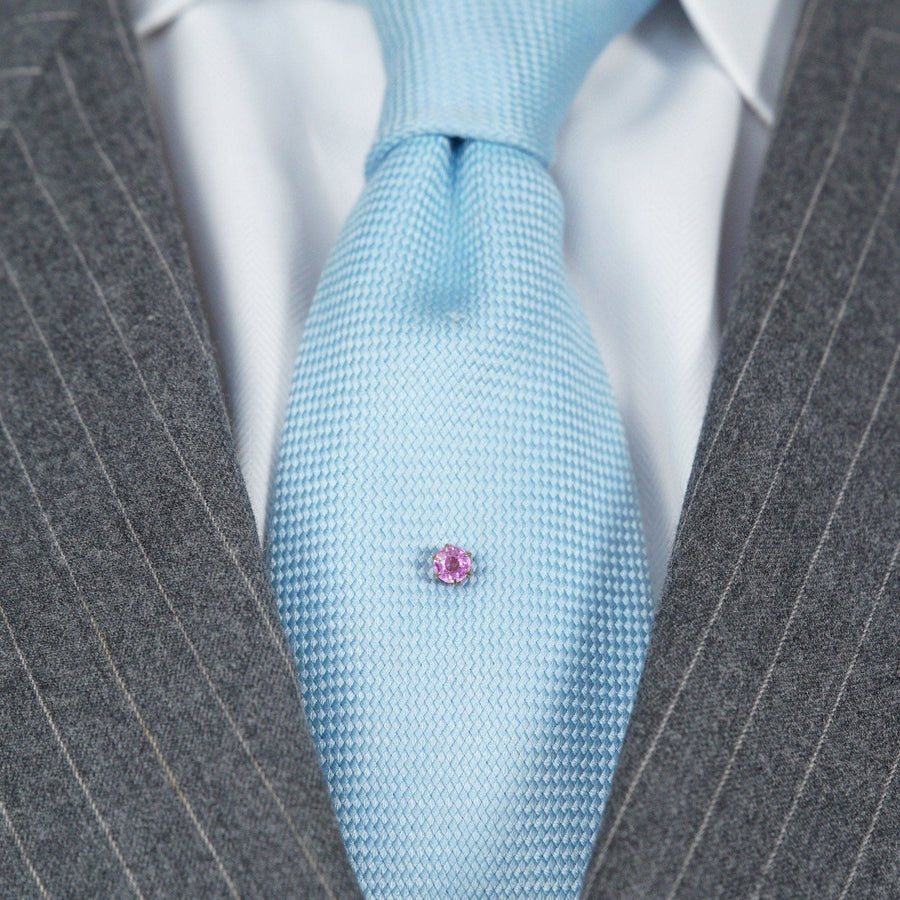 Art Deco Krawattennadel aus 18 Karat Gold mit einem 1-karätigen rosa Saphir auf einer hellblauen Seidenkrawatte.