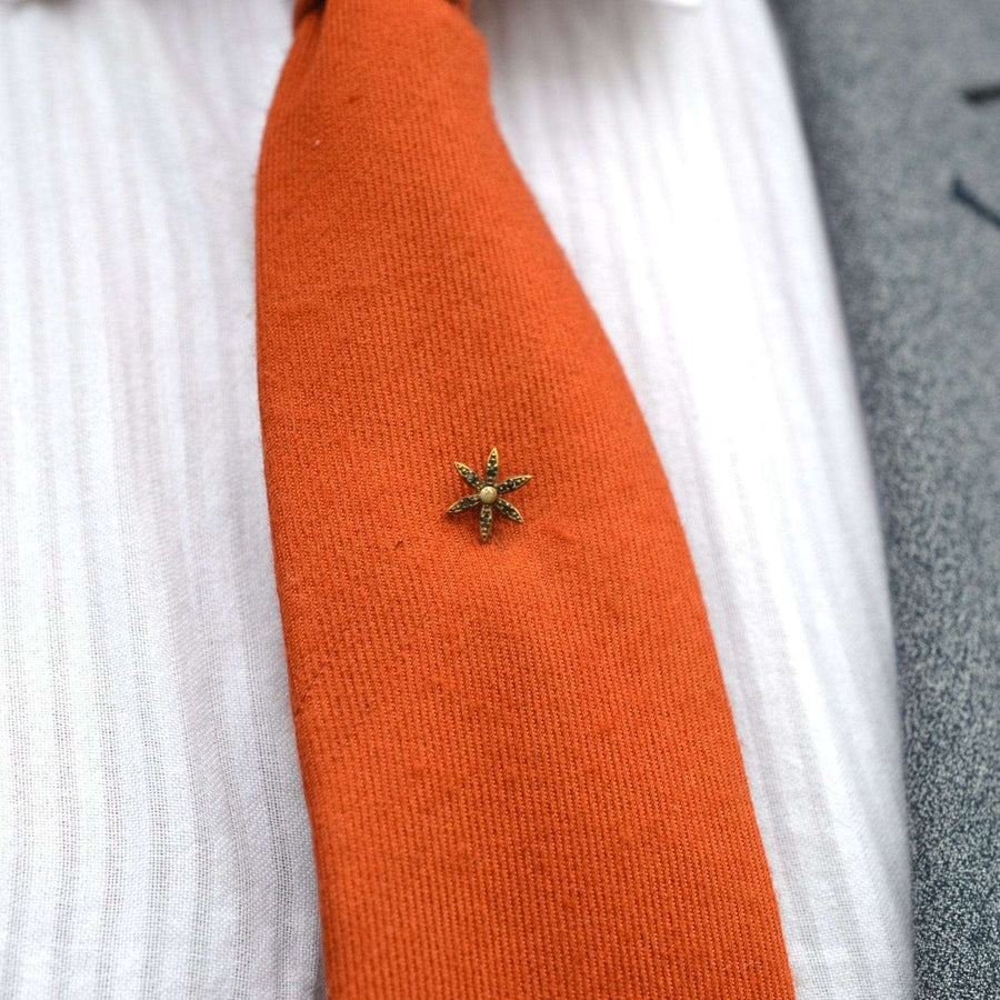 Art Deco Blumen Krawattennadel mit Glasakzenten auf orangefarbener Krawatte, ideal für elegante formelle Kleidung.
