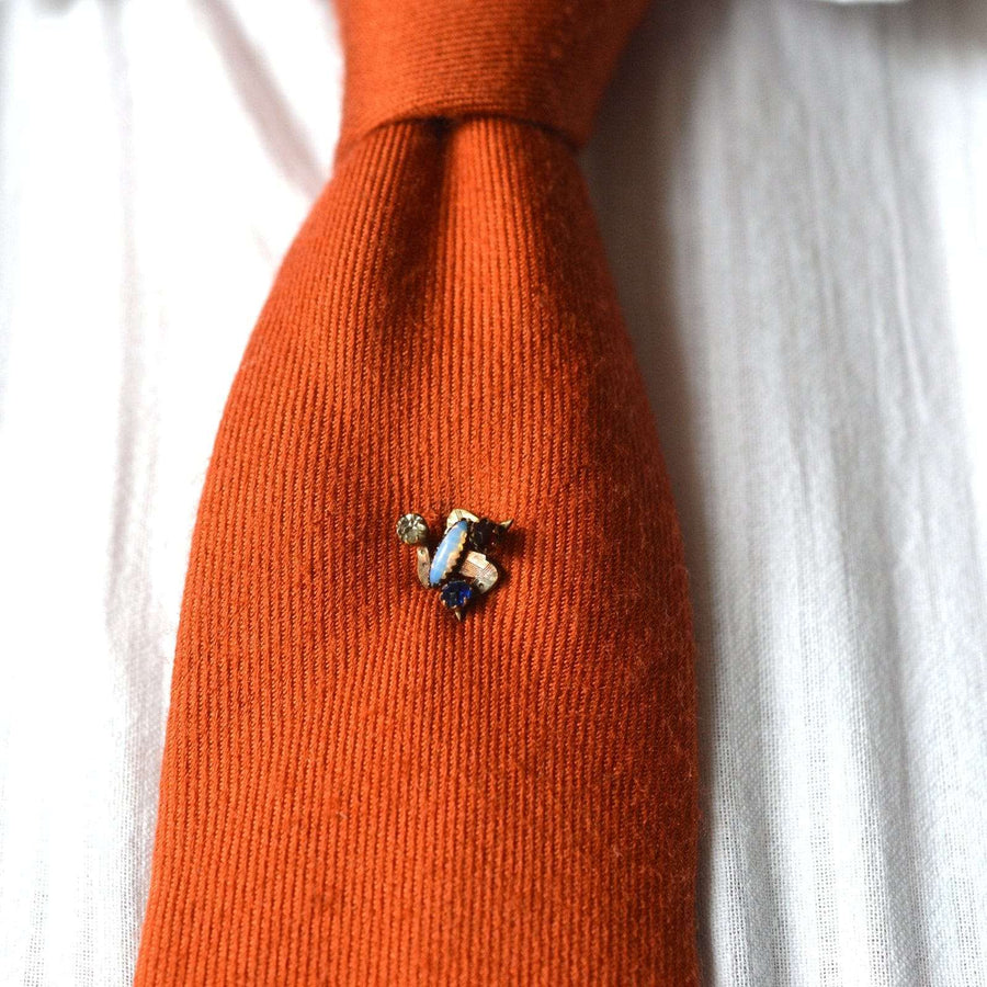 Art Deco Isle of Mann Triskelion Paste Krawattennadel auf einer orangefarbenen Krawatte, mit blauen, roten, weißen und opalen Steinen.