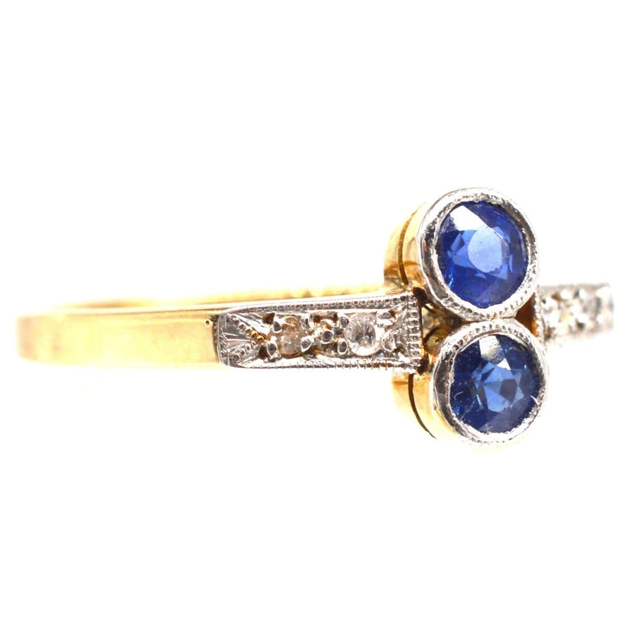 Art-Deco-Ring aus Platin und Gold mit zwei leuchtenden Saphiren und Diamanten, perfekt für Verlobungen oder Geburtstage im September.
