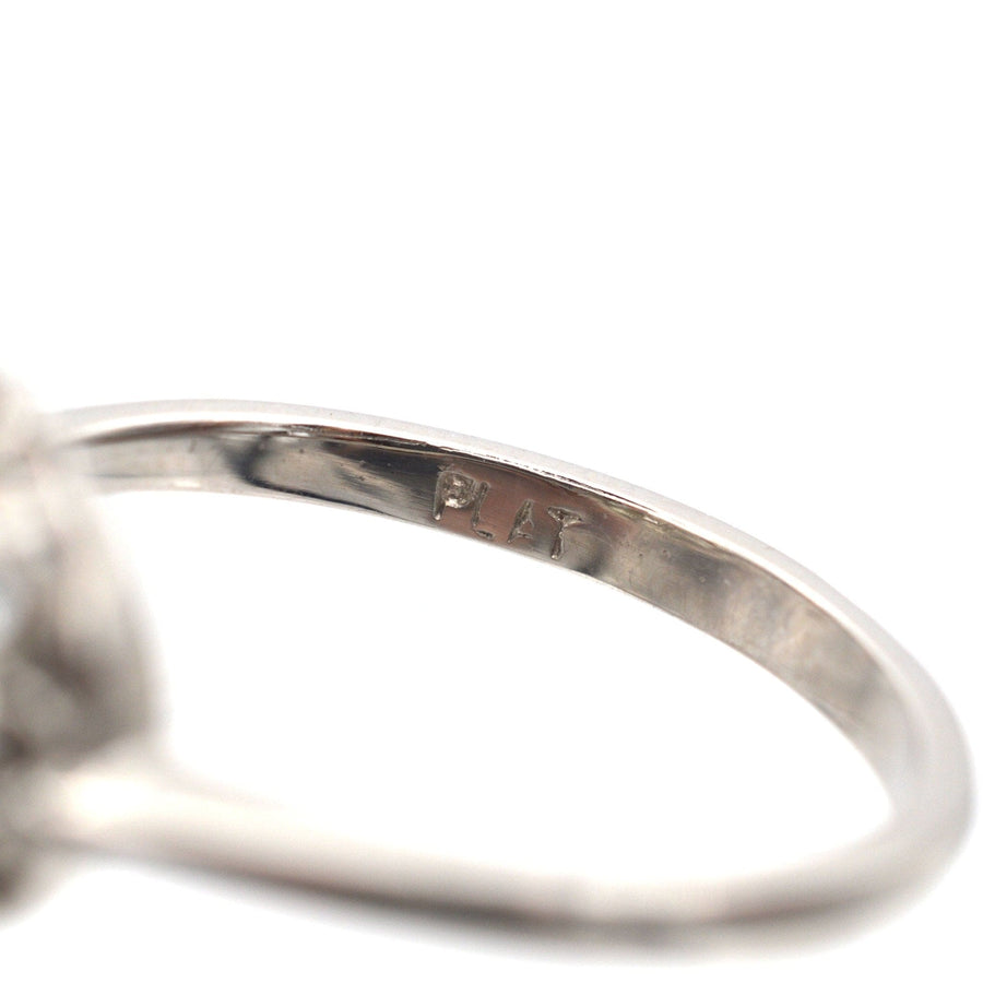 Nahaufnahme eines Platinrings mit eingravierter "PLAT"-Markierung, die seine Qualität für einen Art-Déco-Diamant-Cluster-Ring verdeutlicht.