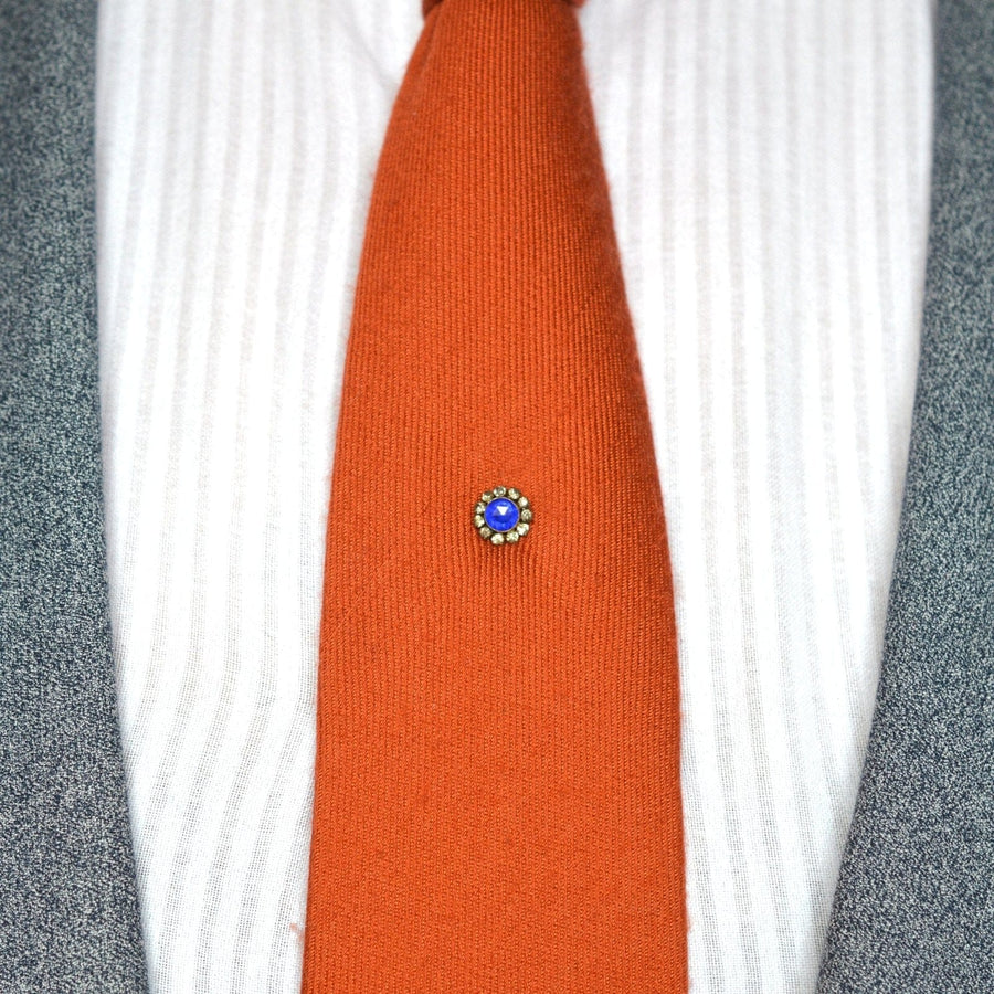 Art-Deco-Krawattennadel mit blauem Saphir im Rosenschliff und weißer Paste auf orangefarbener Krawatte, ein stilvolles und elegantes Accessoire.