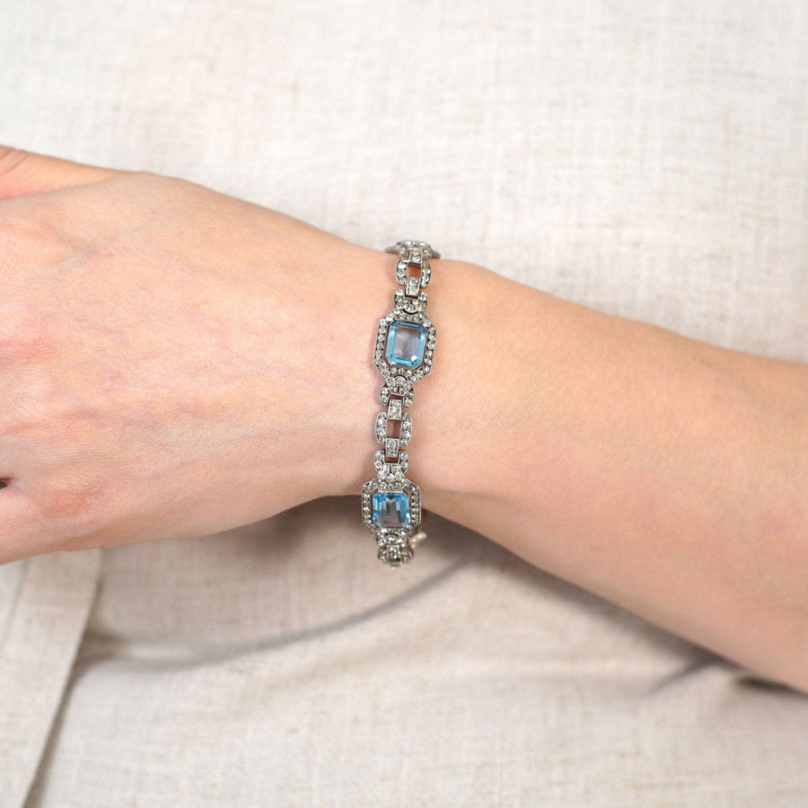 Silberarmband im Art-Déco-Stil mit blauen und weißen Strasssteinen, das ein Vintage-Design am Handgelenk einer Frau präsentiert.