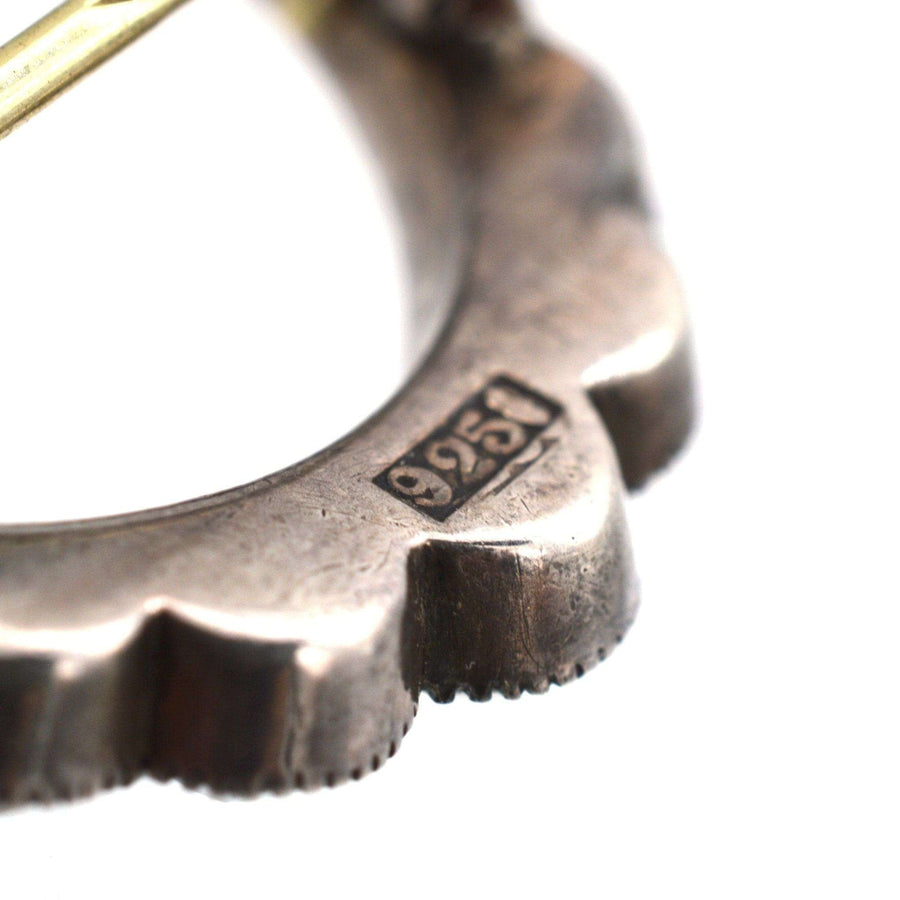 Close-up of a silver crescent moon brooch showing the 925 sterling silver mark for authenticity.