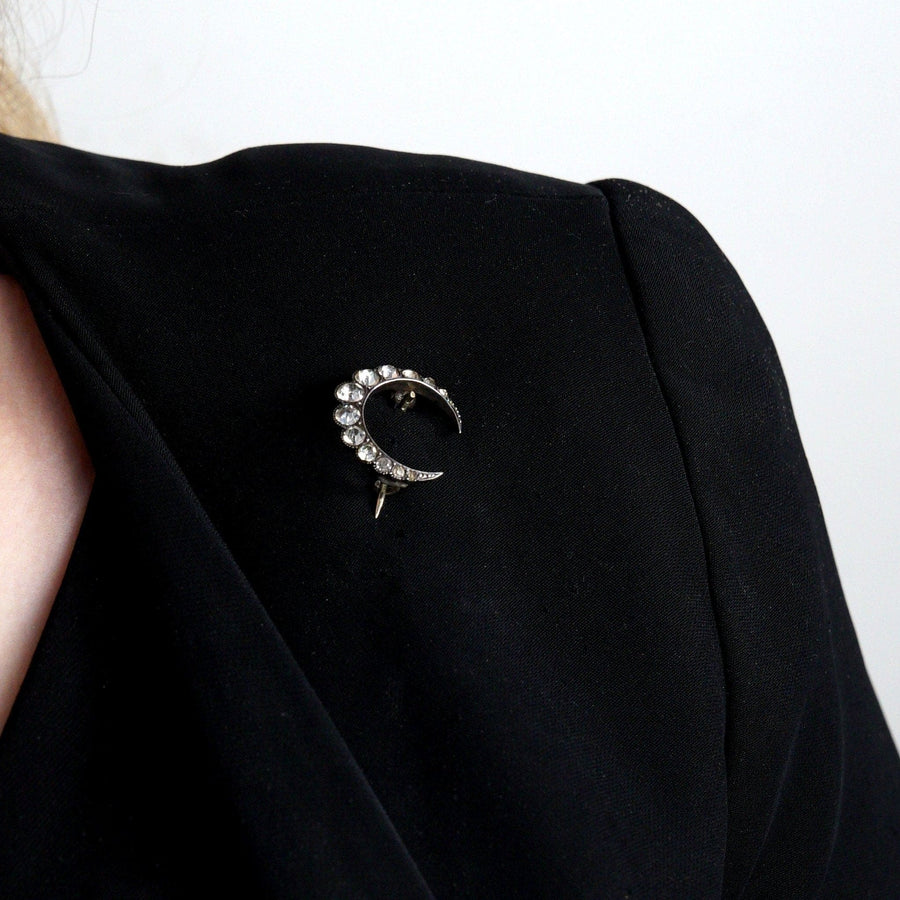 Art Deco silver crescent moon paste brooch on black fabric, showcasing vintage 1930s style costume jewelry.