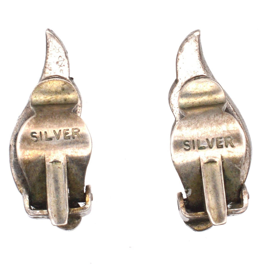 Nahaufnahme von silbernen Art-Déco-Ohrringklammern mit der Aufschrift "SILVER", die komplizierte Designdetails aufweisen.