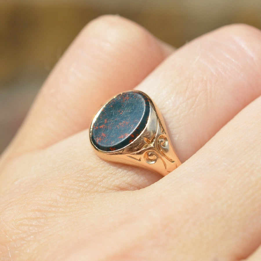 Edwardian 15ct Gold Blutstein Siegelring an der Hand getragen, zeigt komplizierte Design und polierte Steinoberfläche.