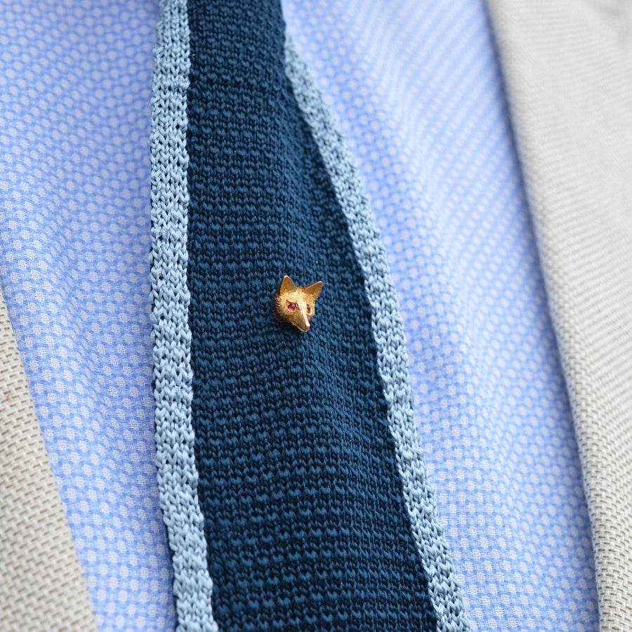 Elegante edwardianische Fuchs-Krawattennadel aus 15 Karat Gold mit granatroten Augen, präsentiert auf einer blauen Strickkrawatte.