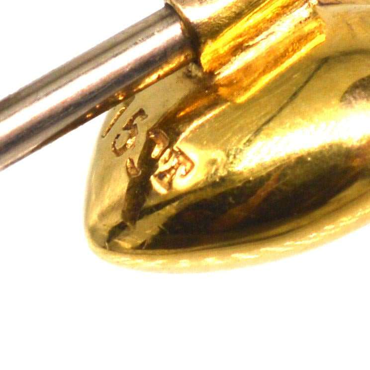 Nahaufnahme einer Herz-Krawattennadel aus 15 Karat Gold, die die Goldpunze und die handwerklichen Details zeigt.
