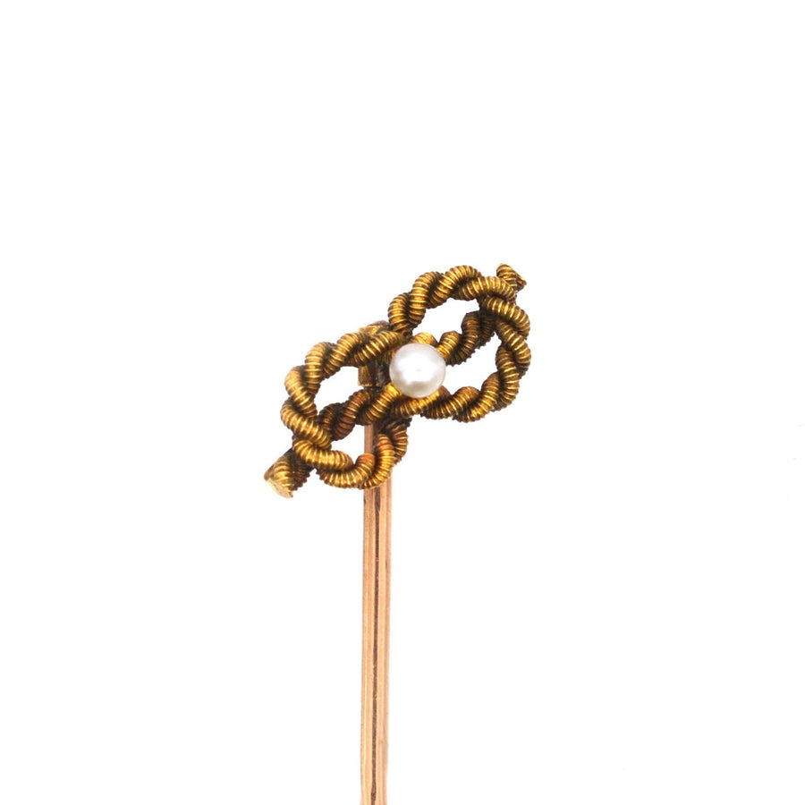 Edwardian 15ct gold lover's knot tie pin with a natural pearl center, symbolizing infinite love.