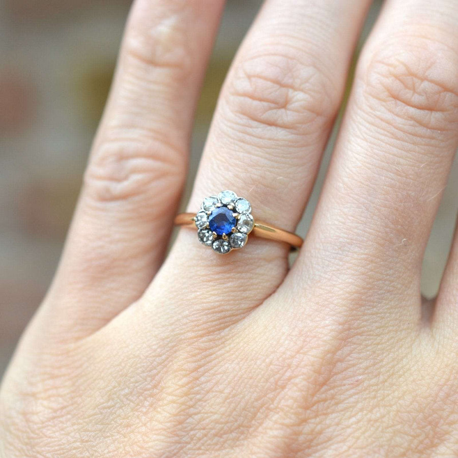 Edwardianischer Ring aus 18-karätigem Gold mit einem Ceylon-Saphir und einem Diamant-Cluster, der auf einer Hand präsentiert wird.