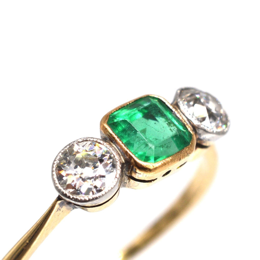 Edwardianischer Ring aus 18 Karat Gold und Platin mit drei Steinen, einem leuchtend grünen Smaragd und schillernden Diamanten.
