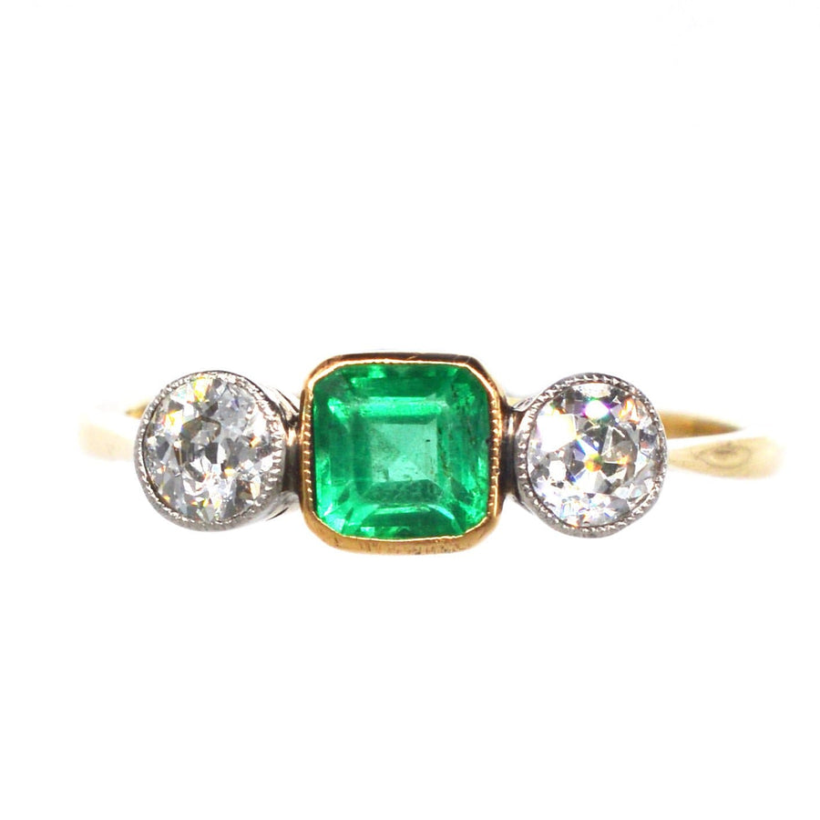 Eleganter edwardianischer Dreisteinring mit einem leuchtenden Smaragd und funkelnden Diamanten in Gold- und Platinfassung.