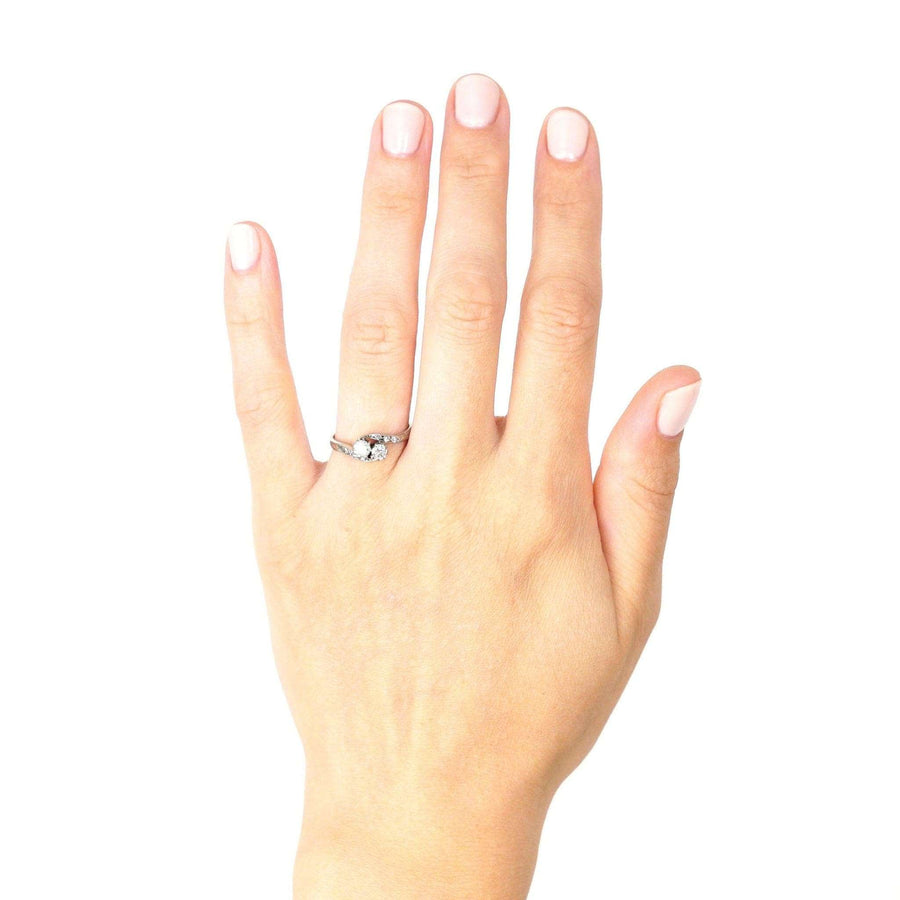 Edwardian 18ct white gold diamond 'Toi et Moi' crossover ring worn on hand, showcating its elegant design and bright diamonds.