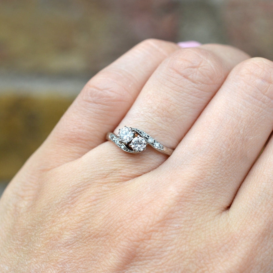 Edwardian 18ct Weißgold Diamant "Toi et Moi" Crossover-Ring auf einer Hand angezeigt.