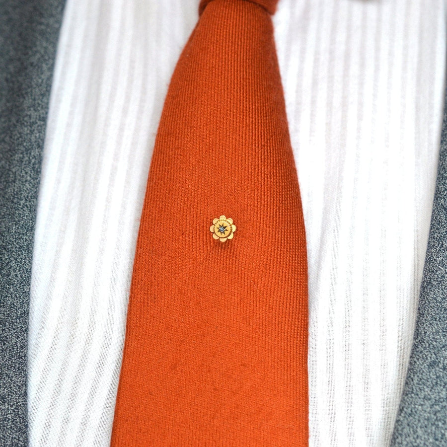 Edwardian 9ct Gold Blume Krawattennadel mit Saphir auf einem orangefarbenen Seidenkrawatte, die Eleganz zu formalen Kleidung.