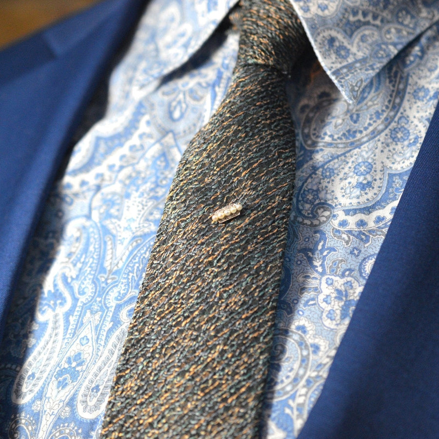 Edwardianische Krawattennadel aus Platin und Gold mit Perlen, die elegant auf einer strukturierten Krawatte und einem Hemd sitzt.