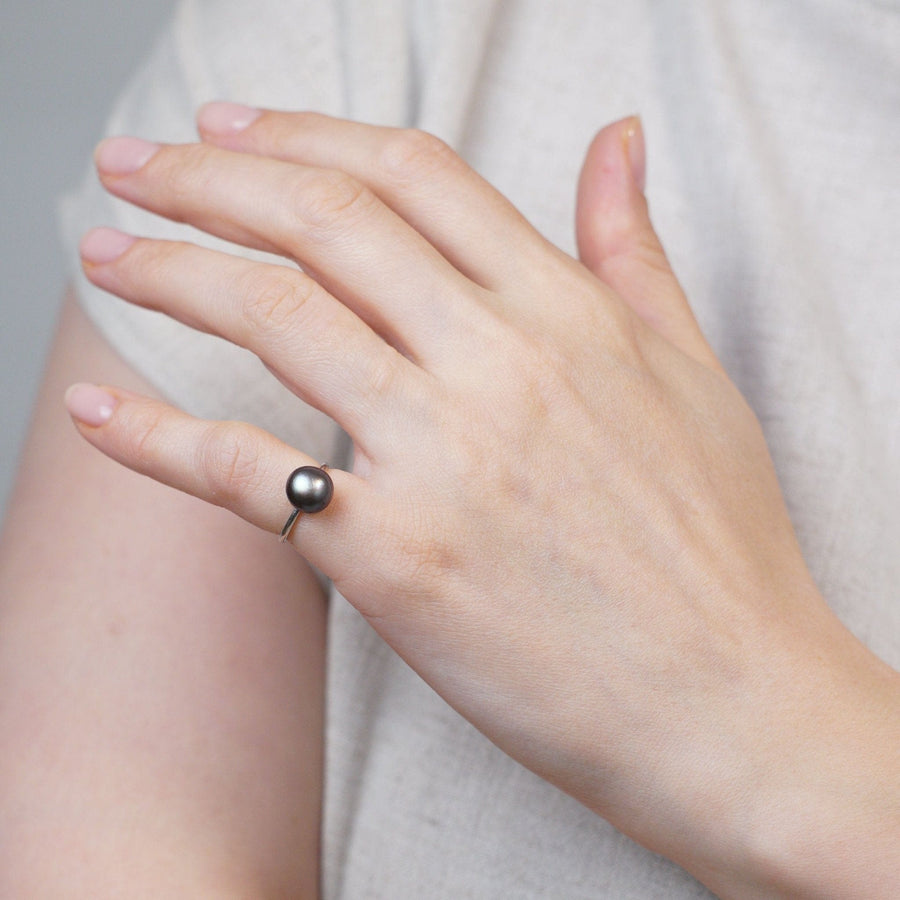 Elegante Hand, die einen Edwardianischen Solitärring aus Platin trägt, der eine natürliche schwarze Salzwasserperle enthält.