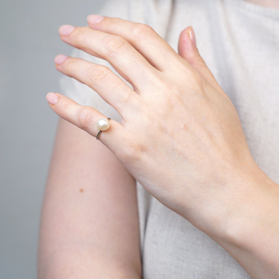 Edwardianischer Solitärring aus Platin mit einer natürlichen Salzwasserperle, die elegant an einer Hand getragen wird.