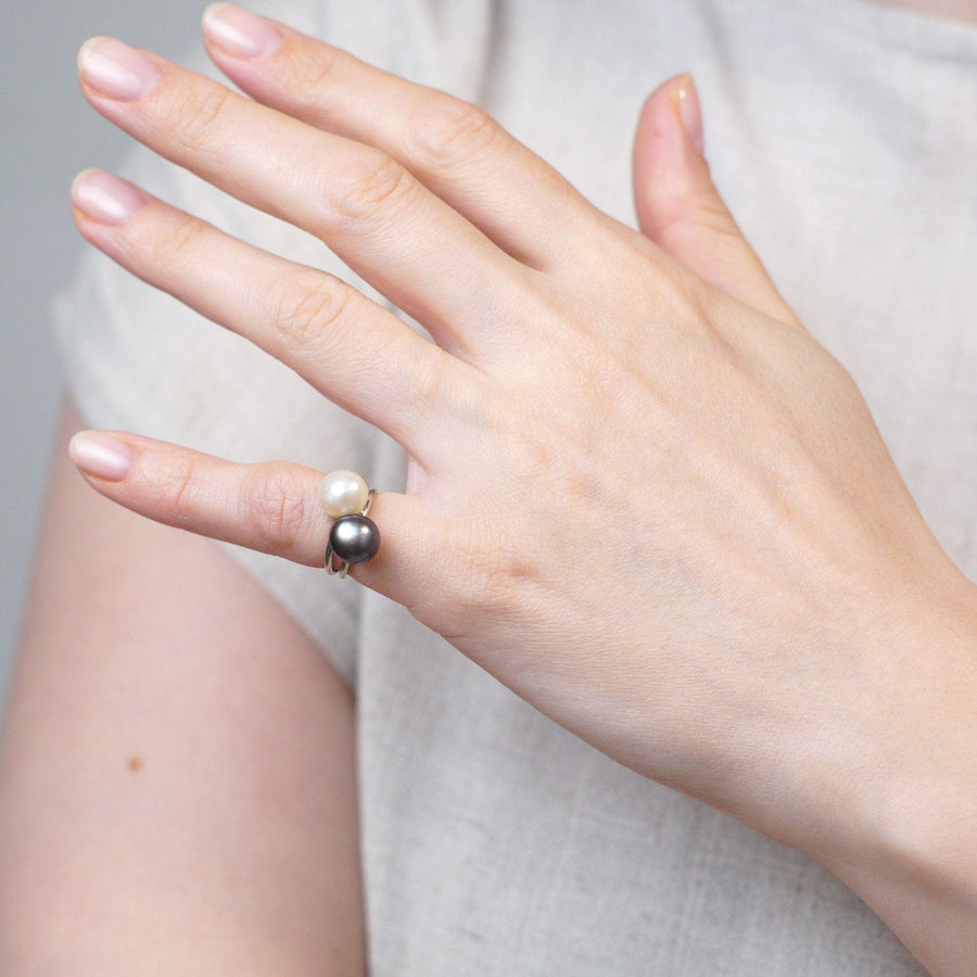 Eine Hand trägt einen Edwardianischen Perlen-Solitärring mit einer natürlichen weißen und schwarzen Salzwasserperle in Platin.