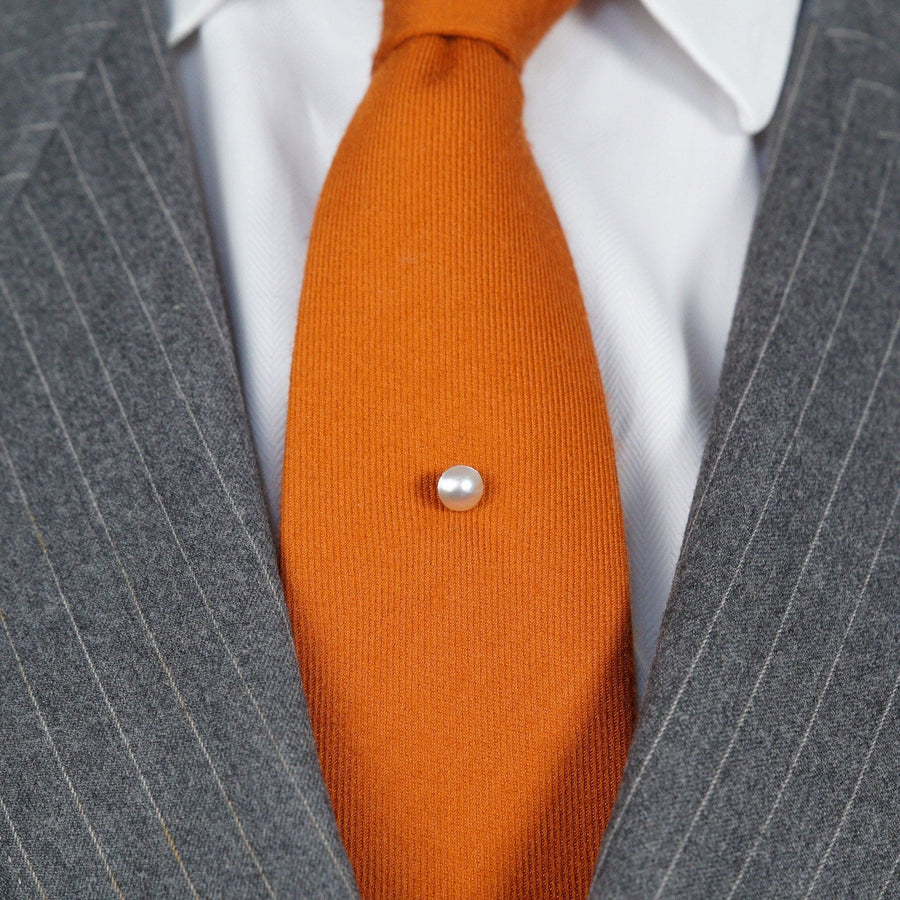Edwardianische Krawattennadel aus Platin mit einer schimmernden Naturperle auf einer leuchtend orangefarbenen Seidenkrawatte, um 1910-1920.