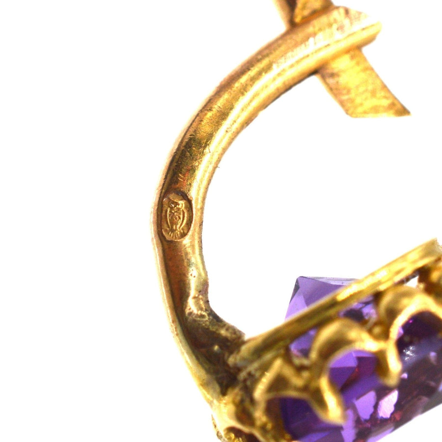 Nahaufnahme eines goldenen Ohrrings mit Amethyst aus dem 19. Jahrhundert, der ein kompliziertes Design und Punzierungsdetails aufweist.