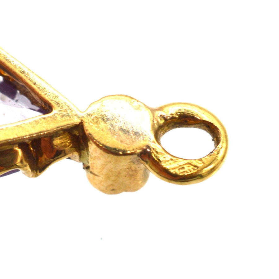 Nahaufnahme einer Vintage-Ohrringfassung aus Gold mit Amethysten und Perlen, die die komplizierte Handwerkskunst hervorheben.