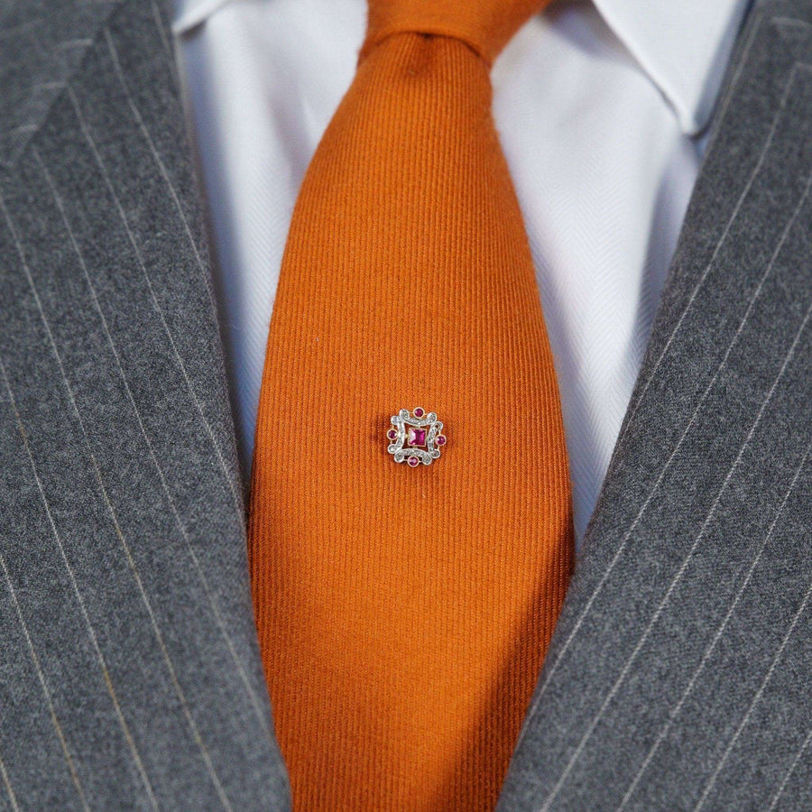 French Belle Époque gold and platinum tie pin with ruby and diamond, worn on an orange tie, showcasing fine craftsmanship.