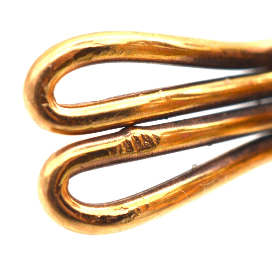 Nahaufnahme einer aufwendig gestalteten goldenen Ohrringklammer, die elegante, fließende Kurven und eine polierte Oberfläche aufweist.