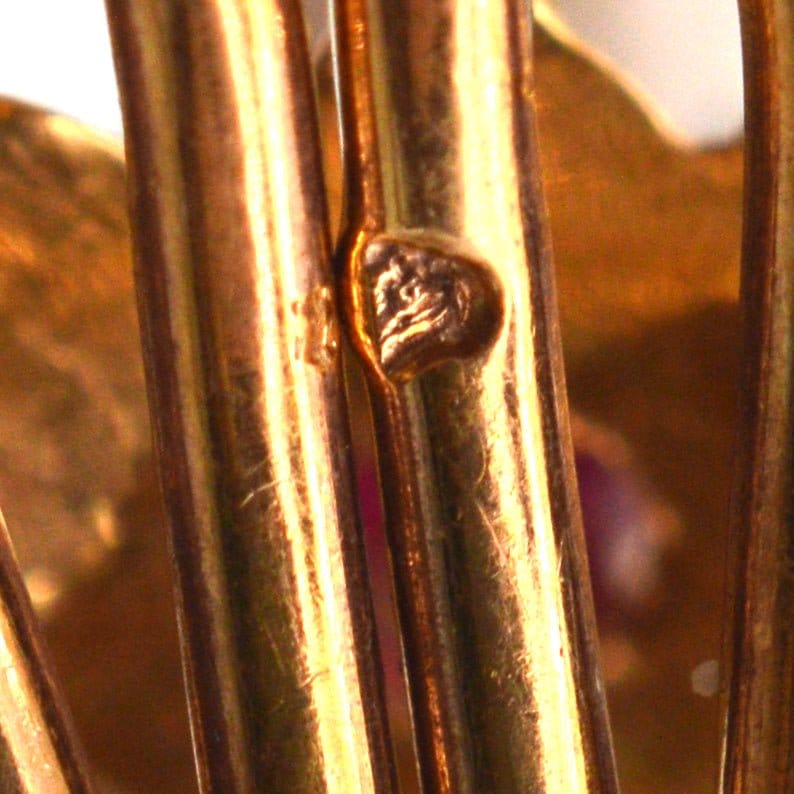 Nahaufnahme des Punzierungszeichens auf Ohrringen aus 18 Karat Gold mit Muschelschalen, die feine Handwerkskunst zeigen.
