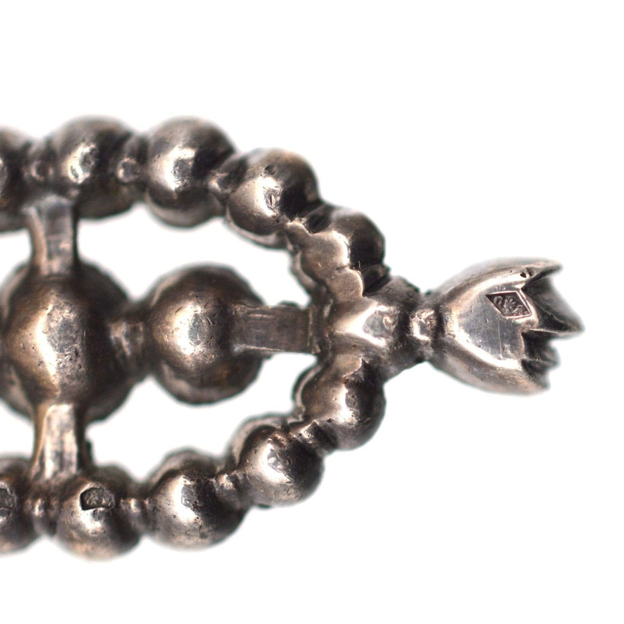 Nahaufnahme eines großen silbernen Ohrrings im portugiesischen Stil, mit gegliedertem Design und eleganten Vintage-Details.