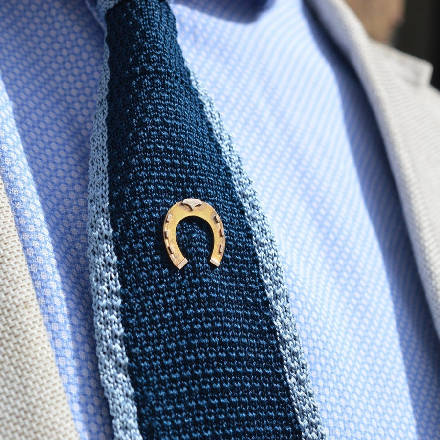 Große viktorianische Hufeisen-Krawattennadel aus 9 Karat Gold auf einer strukturierten blauen Krawatte, die Glück und klassische Eleganz symbolisiert.