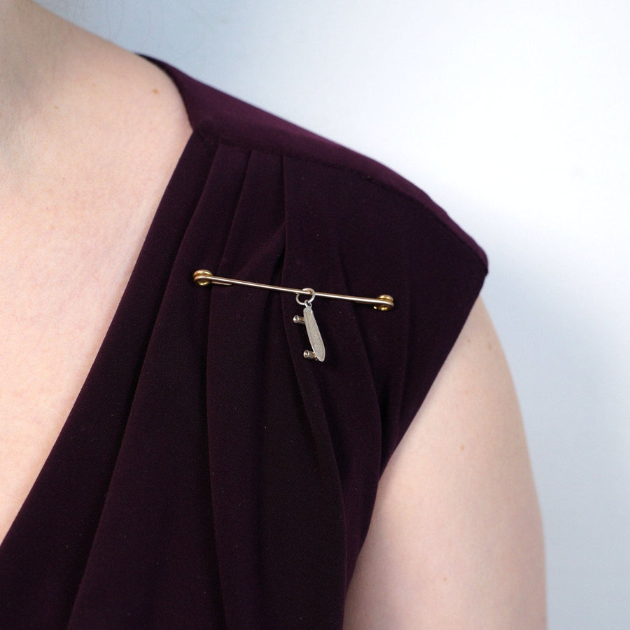 Große viktorianische Sicherheitsnadel aus 9 Karat Gold, die an einem burgunderroten Kleid getragen wird und ihr elegantes Design und ihre historische Bedeutung unterstreicht.
