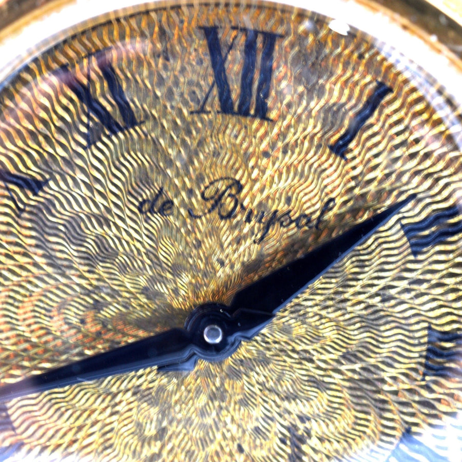 Nahaufnahme des Ziffernblatts der de Brysal-Uhr, das ein kompliziertes Golddesign und blaue Zeiger zeigt.