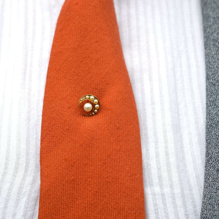 Late Victorian 15ct gold crescent moon tie pin with split pearl star on an orange tie.