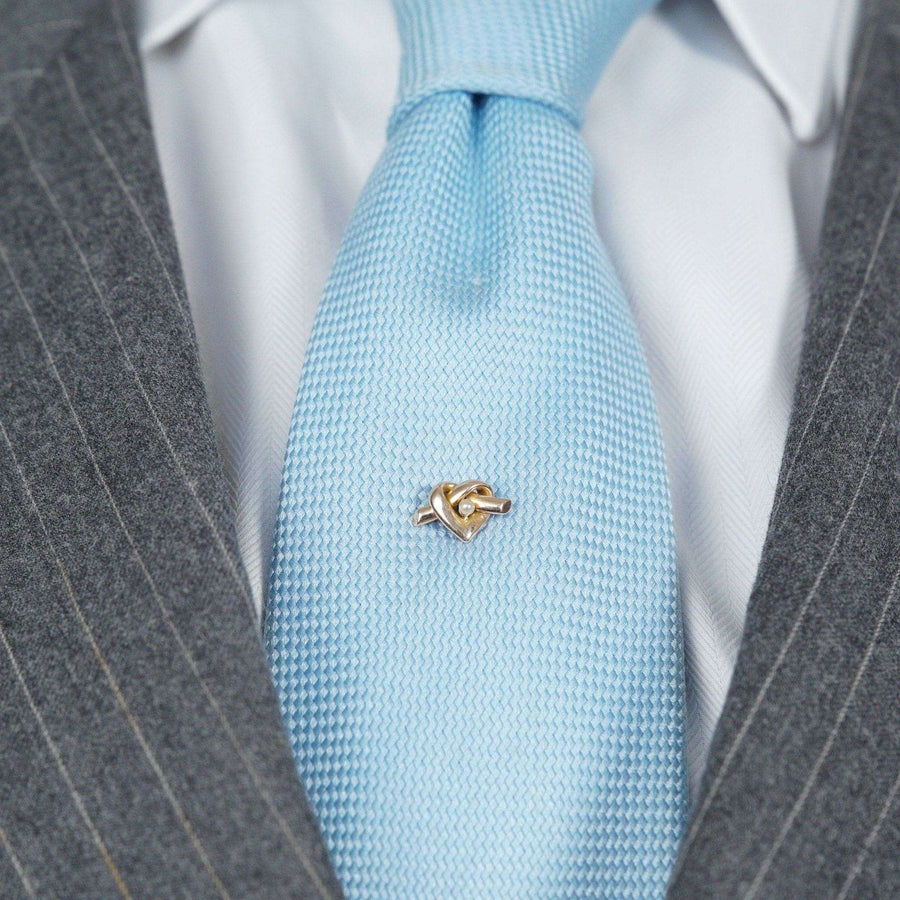 Late Victorian 15ct gold lover's knot tie pin in a heart motif worn on a light blue tie.