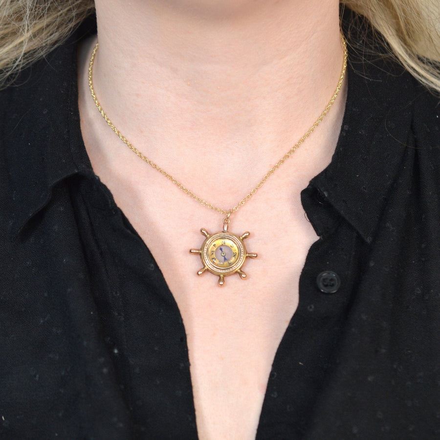 Late Victorian 9ct gold ship wheel compass pendant worn on a black shirt, showcasing vintage nautical design.
