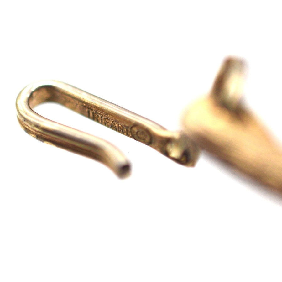 Close-up of a gold-tone earring hook with Trifari stamp, showcasing vintage jewelry craftsmanship.
