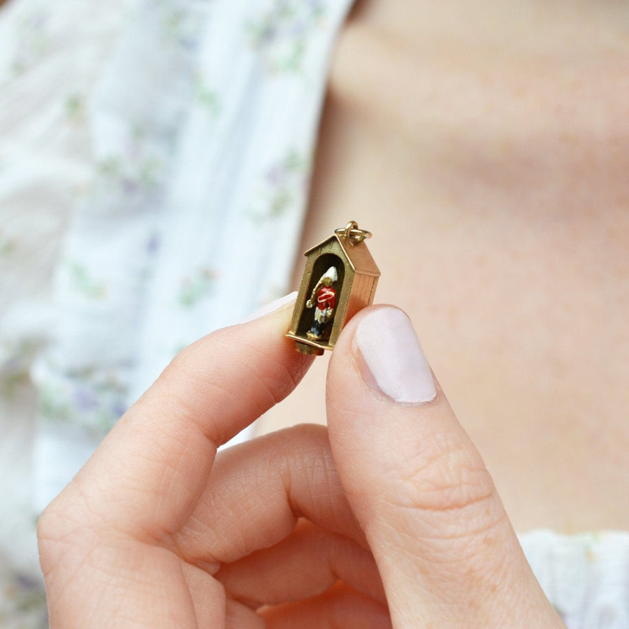Miniatur-Charm der Leibgarde der Königin in einem von einer Hand gehaltenen Wachhäuschen mit einem exquisiten Gold- und Emaille-Design.