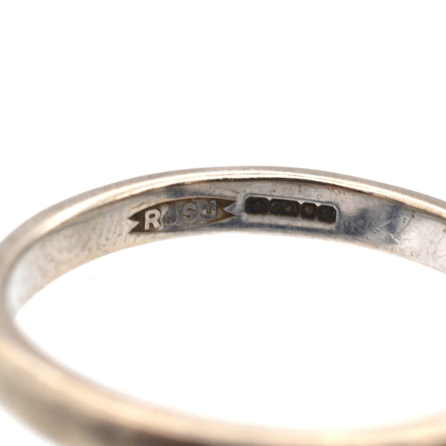 Nahaufnahme eines modernen Eherings aus 18 Karat Weißgold mit Punzierung, der sein schlichtes und elegantes Design zeigt.